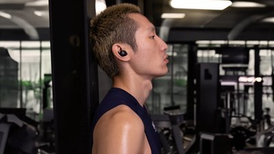 Ein Sportler mit Sennheiser "Momentum Sport" In-Ear-Kopfhörern im Fitnessstudio